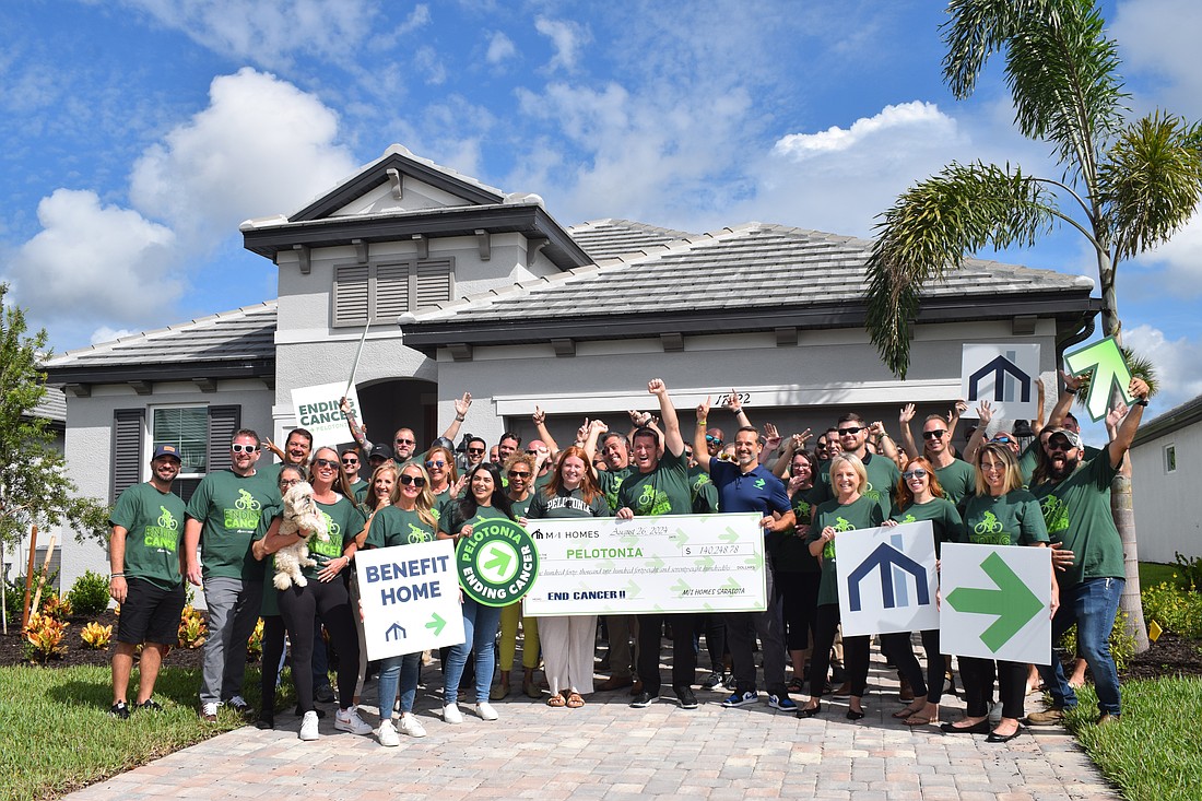 M/I Homes of Sarasota employees and representatives from Pelotonia cheer for the $140,248 M/I Homes' Benefit Home raised for Pelotonia.