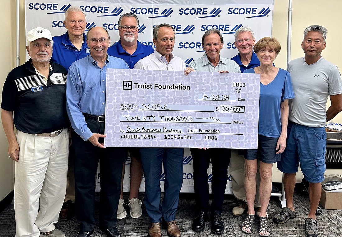 SCORE certified mentors with the $20,000 check from the Truist Foundation. Front row from left: Tony Flores; Jack Phifer; Bob Ludlow, vice president of Truist Financial; Phil Bailey; and Barbara Rhees. Back row: Steve Barnett; Jeff Carlin, chair of SCORE Chapter 87; Dave Ferguson; and
Jim Brundage. Courtesy photo