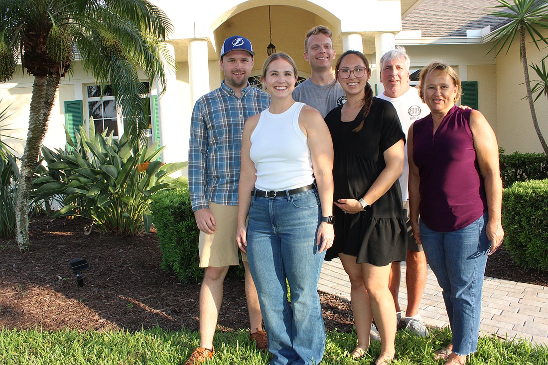 Derek and Stephanie Schmitt, Kirsten (Schmitt) and Trevor Lovett, and Bob and Charleen Schmitt stand in front of Bob and Charleen's Summerfield home.