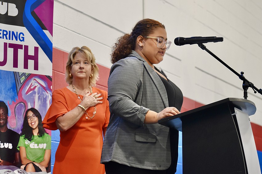 Former Senator Lisa Carlton stands behind Boys & Girls Clubs member Leyra O., a junior at Sarasota Military Academy, as she recites the pledge of allegiance.