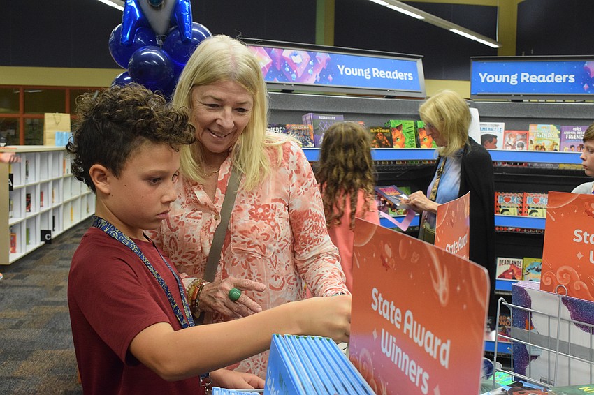 Fifth grader Grayson Figueroa peruses the state award winning books with his grandmother Cheryl McGrew.