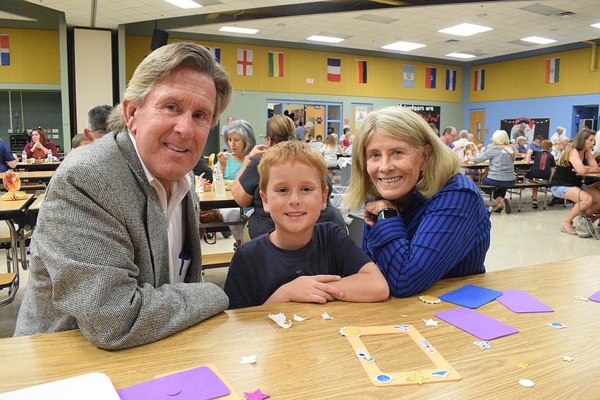 Mike Doyle works on a craft with his grandson Charlie Doyle, a first grader, and his wife, Lynne Doyle. Before the craft, the Doyles browsed the books available at the book fair, which Mike Doyle says was great.