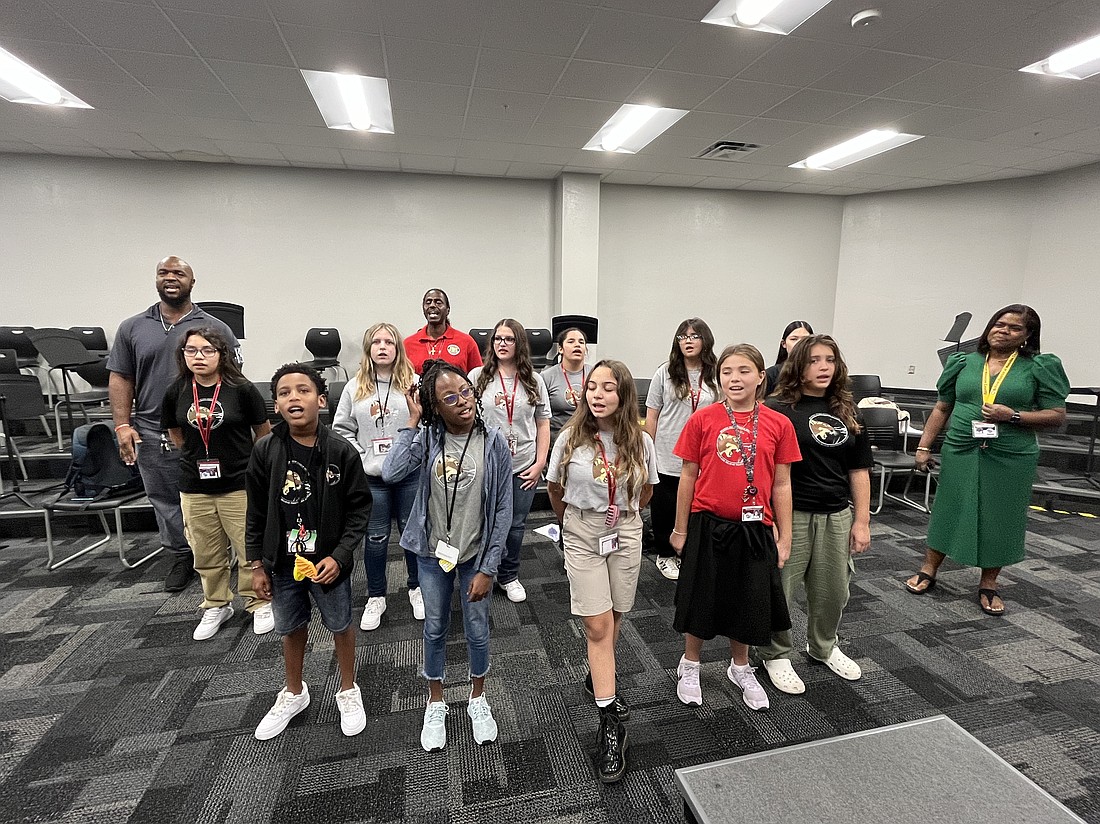 Braden River Middle School students, custodians and Principal Kimberlain Zenon-Richardson (right) sing the new school song.