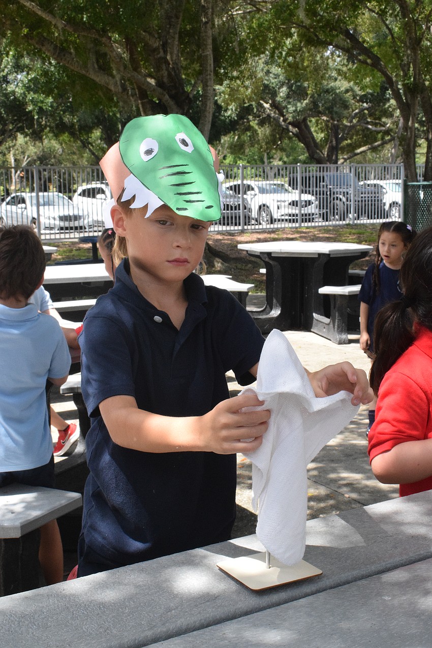 Kindergartner Zander Nooney wears the alligator hat he made with pride as he makes an oyster rag pot. Nooney and his class studied American Alligators as part of Everglades Week.