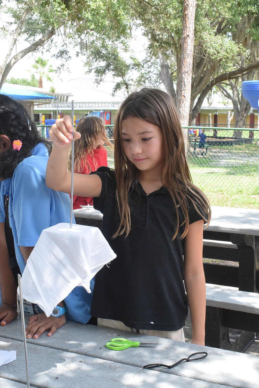 Julie Knaus, a third grader, twirls her oyster rag pot around before adding it to the hundreds of others that Braden River Elementary students created for Oyster River Ecology Inc.