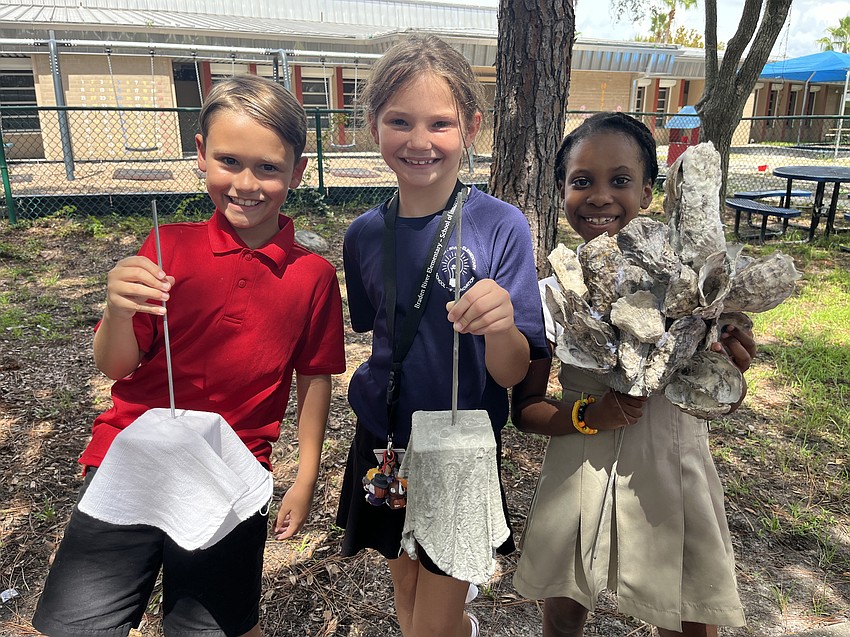 Third graders Ryan Burchett, Addison Delazzer and Eliana Gabriel show the progress of an oyster rag pot. It starts as a spike with a wooden square covered by a white rag. Then it is covered in cement and placed at the bottom of a river. Oysters attach to the pot and begin filtering water.