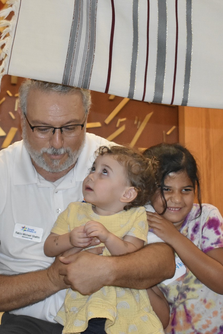 Rabbi Michael Shefrin, his daughter Maya Shefrin, 2, and Kohav Weiman, 5, gather        gather under the Tallit, a prayer shawl, to acknowledge children born in the month of September.