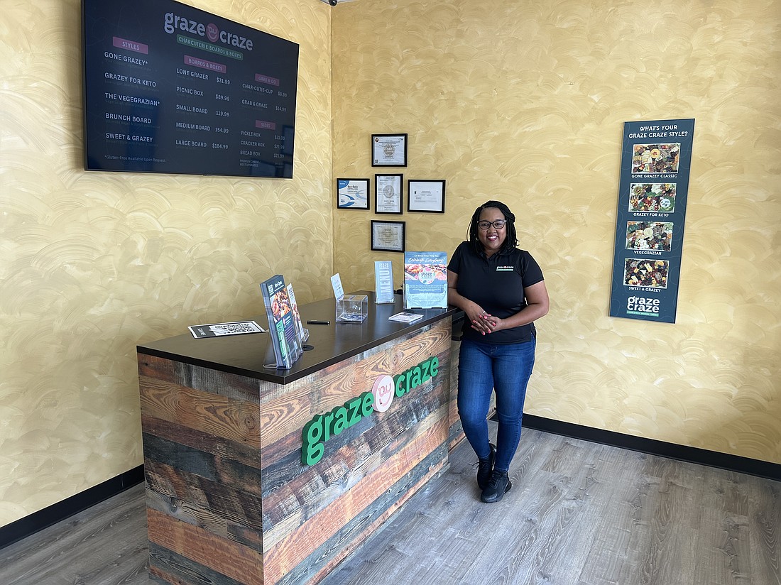 Graze Craze franchisee Canedra Darby at a counter at the store’s entrance, where menus are available in print and on a video screen.