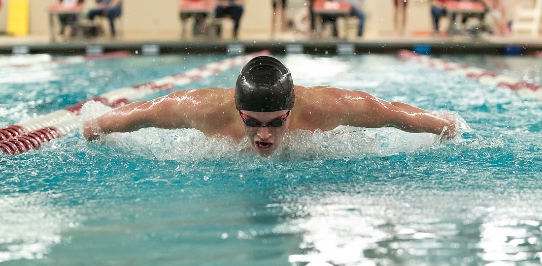 A young male swimmer swims the butterfly at a swimming meet