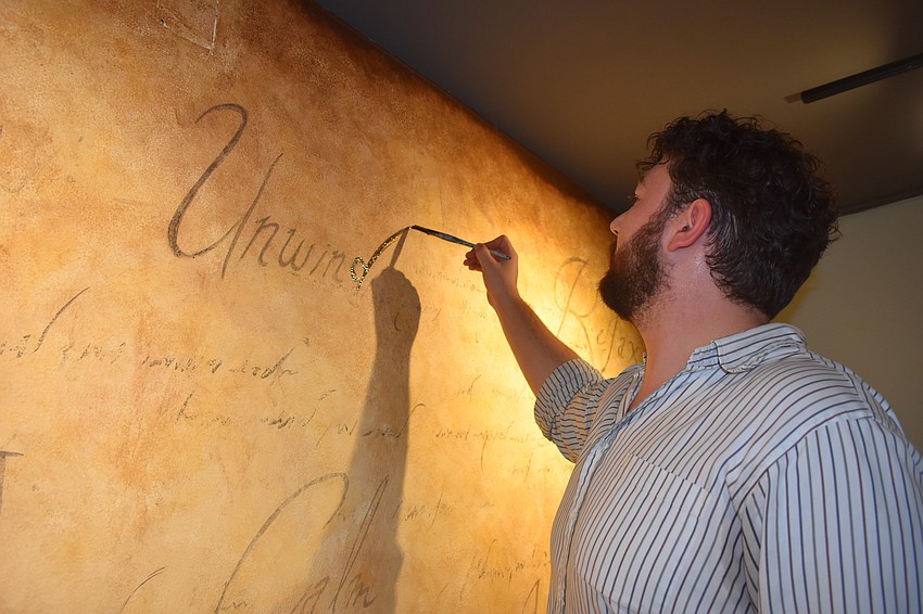 Ringling College graduate Joshua Hardinger adds to the mural he created in the space.