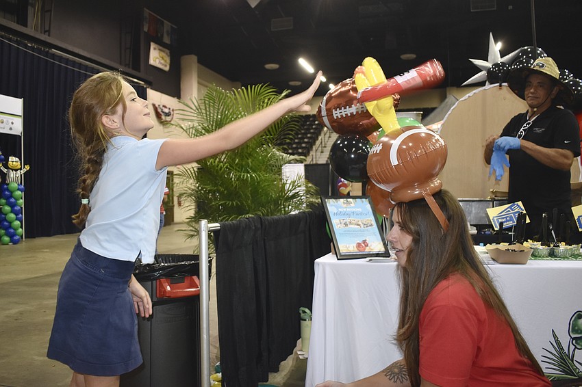 Lakewood Ranch's Nadiyah Aljukic, 7, scores big as she plays ring toss on Devin Andersen's hat, at the table of the Ellenton restaurant Whiskey Joe's where Alan Medeiros is also pictured. Aljukic walked away from the table with a plush gator.