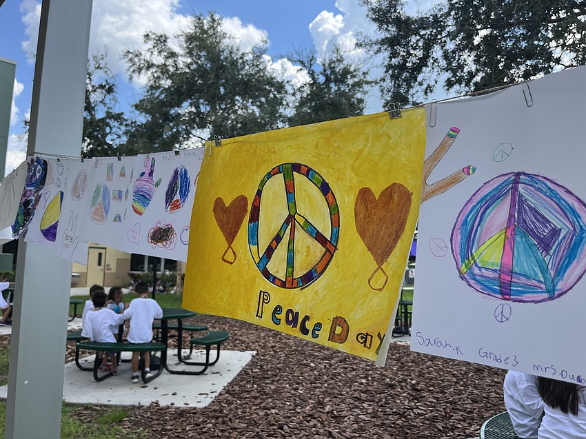 Students create artwork with a message of peace that lines the walkway to the main entrance of the school.
