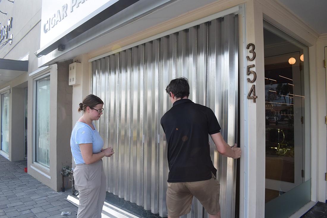 Carolyn Conner and Jake Wright put hurricane shutters at Cigar Paradise.