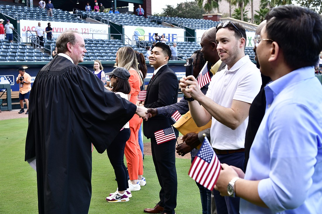 Chief U.S. District Judge for the Middle District of Florida Timothy Corrigan with new American citizens after he administered the Oath of Allegiance at a naturalization ceremony Sept. 17.