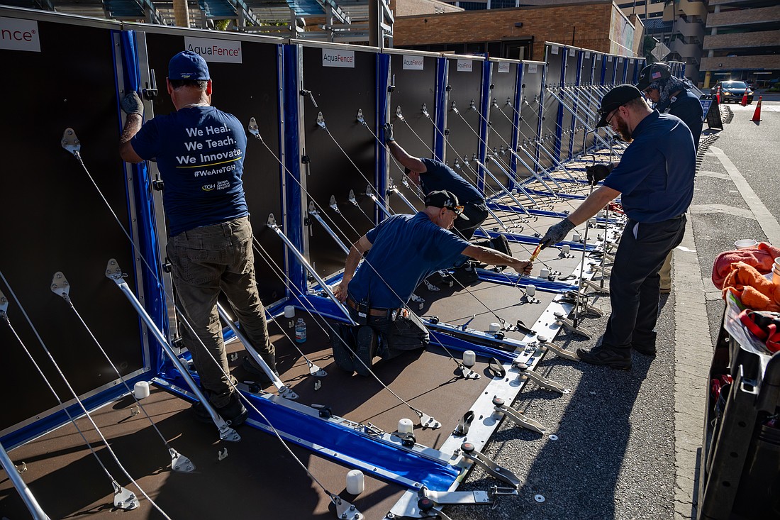 Members of the Tampa General Hospital facilities team install AquaFence panels around the lower areas of the hospital campus on Sept. 24, 2024 in preparation for potential Tropical Cyclone Nine, which is forecast to become Hurricane Helene. The AuqaFence panels are designed to limit flood water damage.