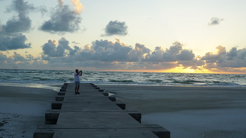 Town Manager Howard Tipton takes pictures of the exposed groin field on the north end beach, one of which he's standing on. These are supposed to be covered with sand.