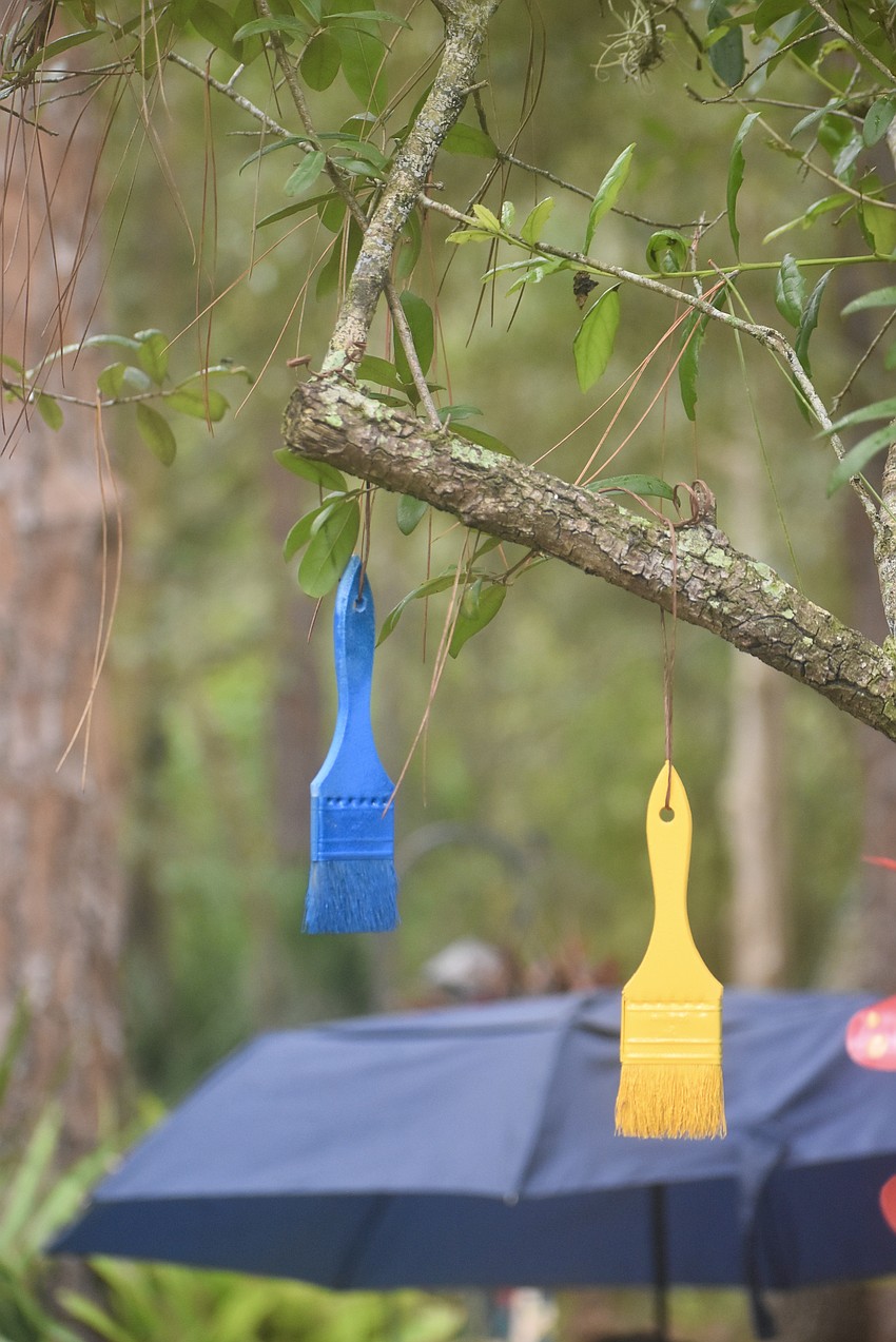 Colorful paintbrushes hang from the trees on the Peaceful Path.