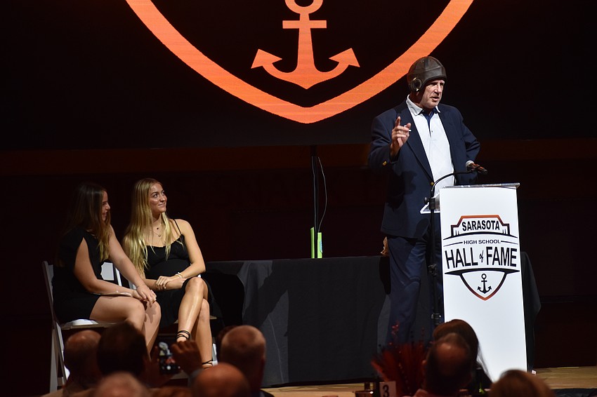 Sarasota High School students and award presenters Harley Renner and Parker Mayforth watch in amusement as Paul Piuorowski tries on a gift he received at the event: his old football helmet.