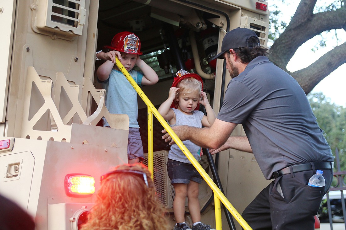 A man helps a child out from OBPD's MWRAP during National Night Out. Photo by Jarleene Almenas