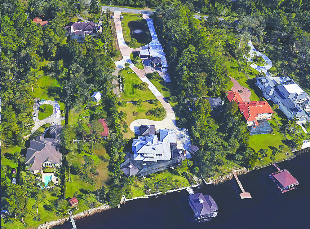 Intracoastal Waterway two-story home features five bedrooms, six full and one half-bathrooms, office, screened pool and patio, outdoor kitchen, porches, attached and detached garage with 14 car spaces, putting green, boathouse and dock.