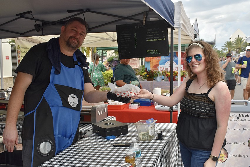 Andor Budai passes a homemade Hungarian sausage to Waterside Place resident Dakota Kiss. Budai makes the sausages fresh each week for his truck, Andor's Kitchen.