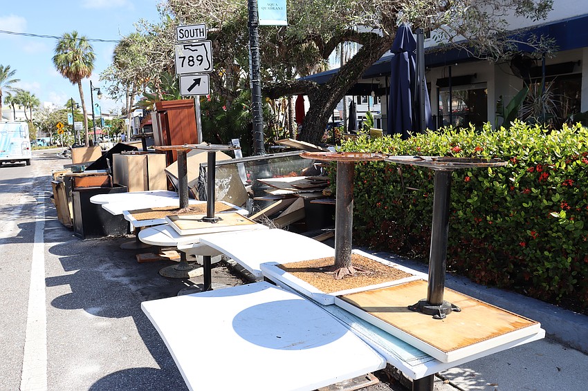 Tables formerly inside Crab & Fin at St. Armands Circle await debris removal.