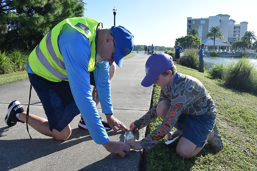 Volunteer ranger Chris Armstrong measures Orlando 10-year-old Parker Ramos' fish. Four minutes later, Ramos caught another fish.
