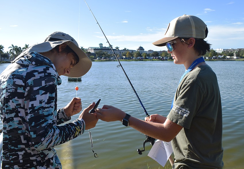 Sarasota 13-year-olds Matt Pirogov and Cru Raines help each other clear their bait and lines so they can continue fishing.