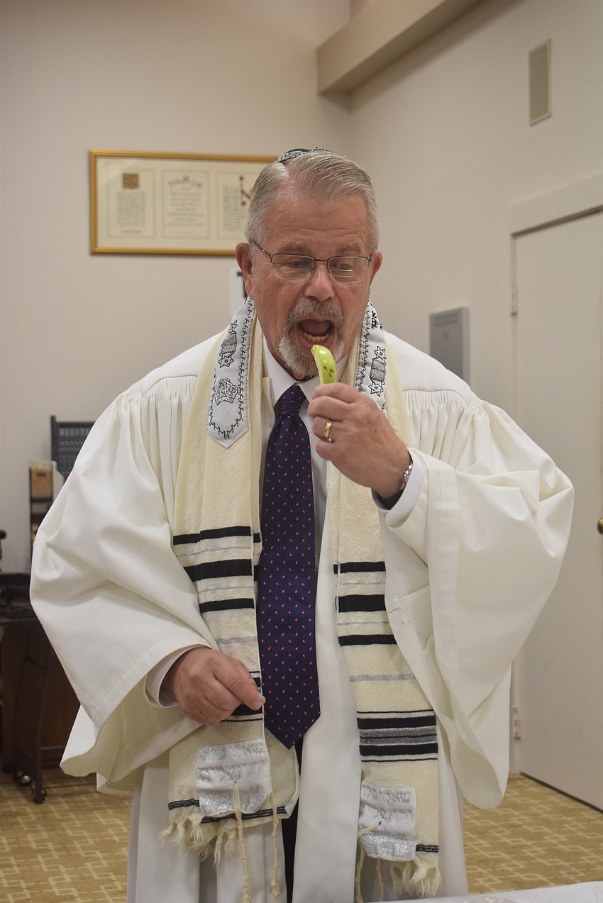 Rabbi Stephen Sniderman eating apple dipped in honey for a sweet year at Temple Beth Israel.