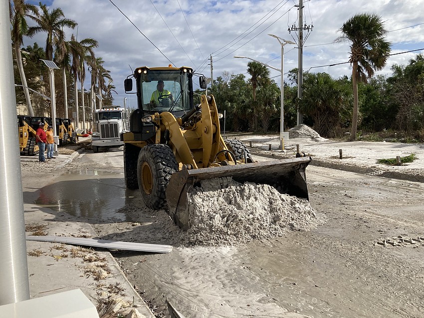 A front loader clears a layer of sand from Ben Franklin Drive on Lido Key, leftover from Hurricane Helene.