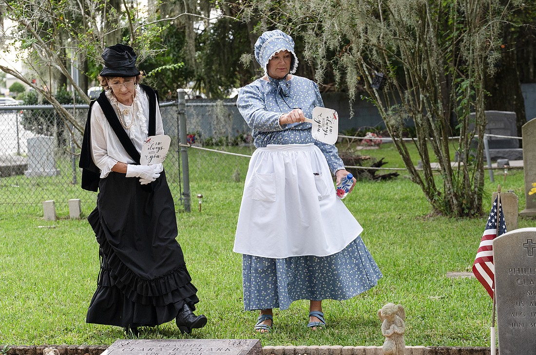 Reenactors Laurie Taylor (left) and Ormond Beach Historical Society president Mary Smith look at headstones at the Pilgrims Rest Cemetery. Photo by Michele Meyers