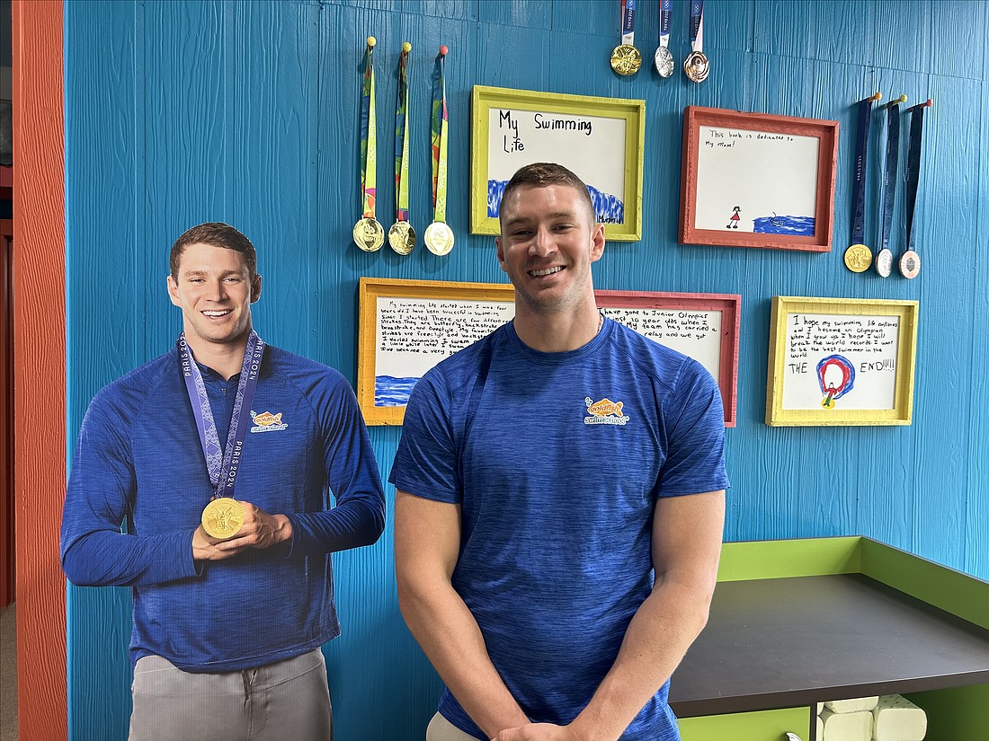 Olympian Ryan Murphy in front of a mural of his childhood drawings and Olympic medals: “We’re very serious about teaching your children to swim and to swim the right way, but we also know that the best way to learn is to have a good time while doing it.”