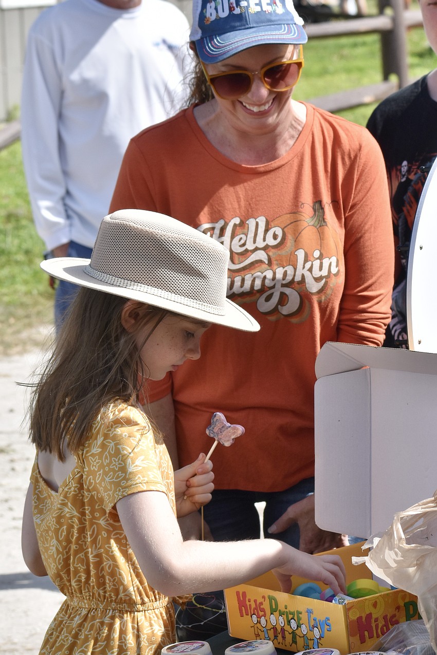 Lydia Carroll, 8, selects a prize after spinning a wheel of fortune, while Brandi Carroll looks on.