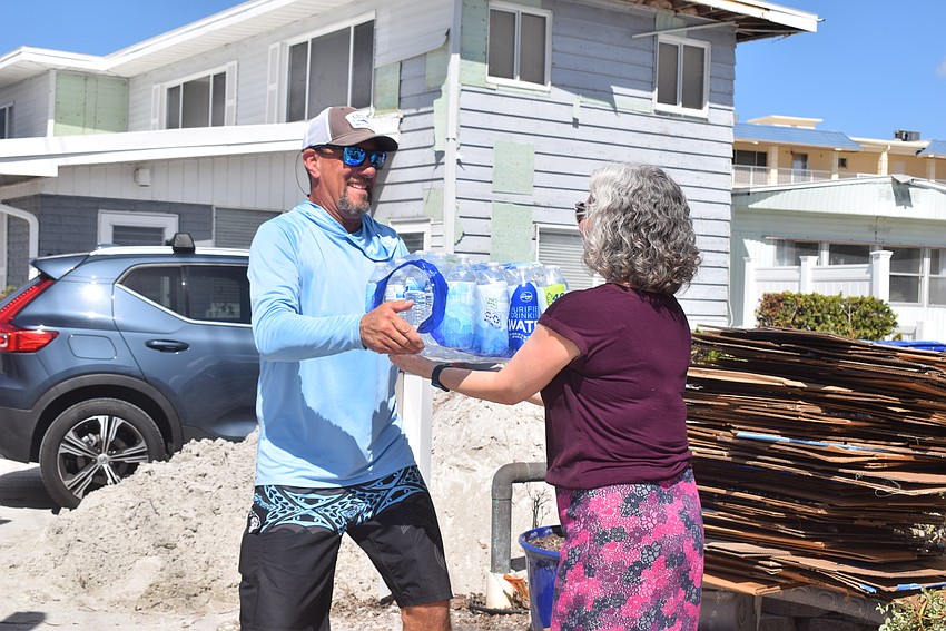 Tony Falagario handing water collected by Milton High School to Julie Swanger from Northern Trust.