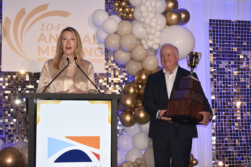 Emily Walsh offers a speech as Robert Lane, managing shareholder of Kerkering Barberio, prepares to present the award.