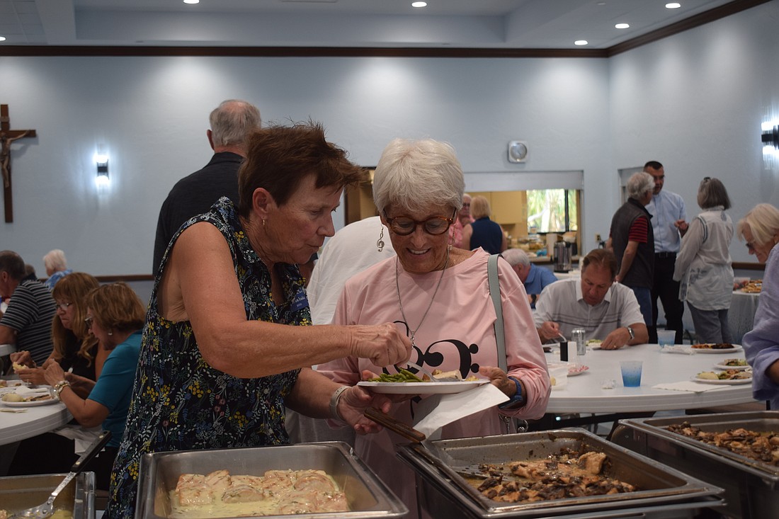 Mary Lou Ivaska serving Connie DiMaggio at the St. Mary Star of the Sea potluck.