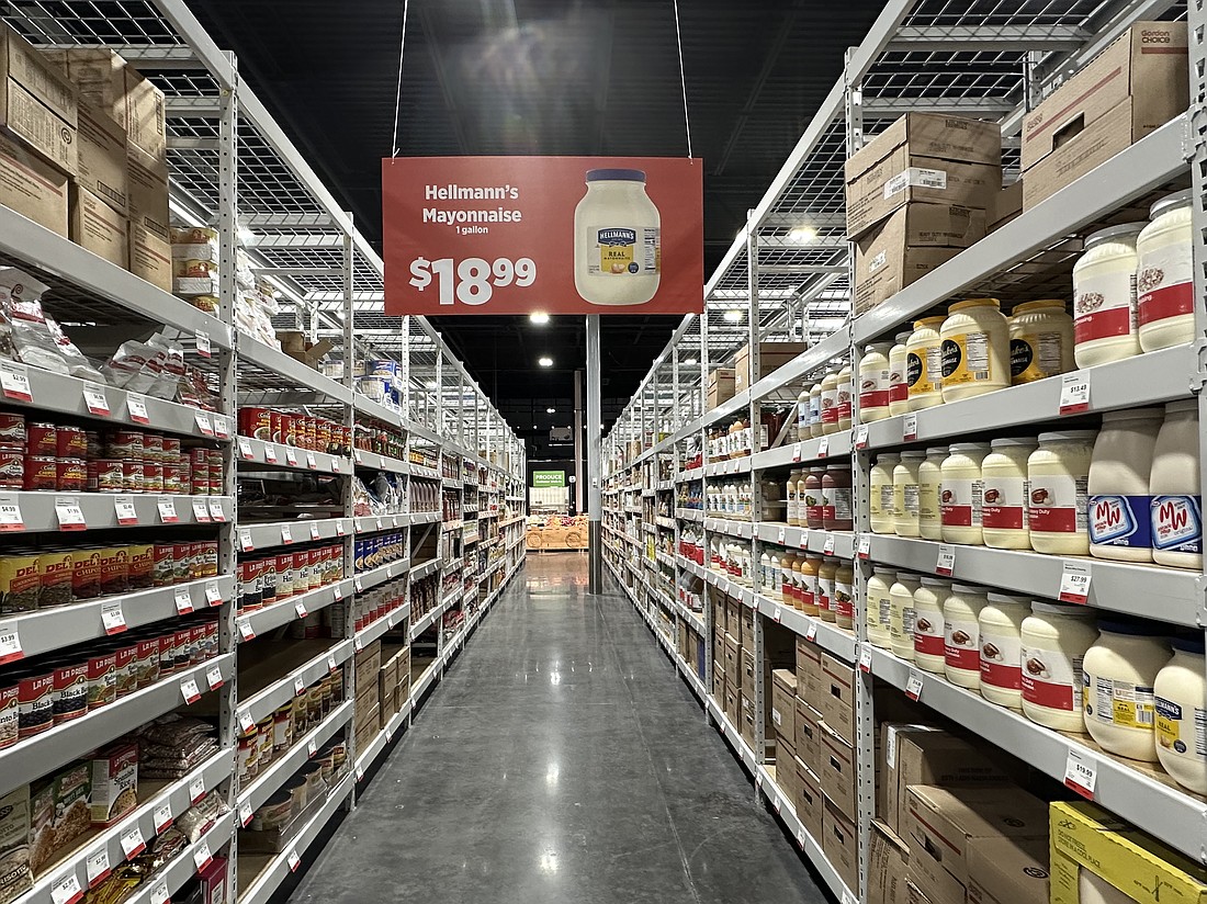 Aisles are stacked with cans and containers of food, including a gallon of Hellmann's mayonnaise at $18.99.