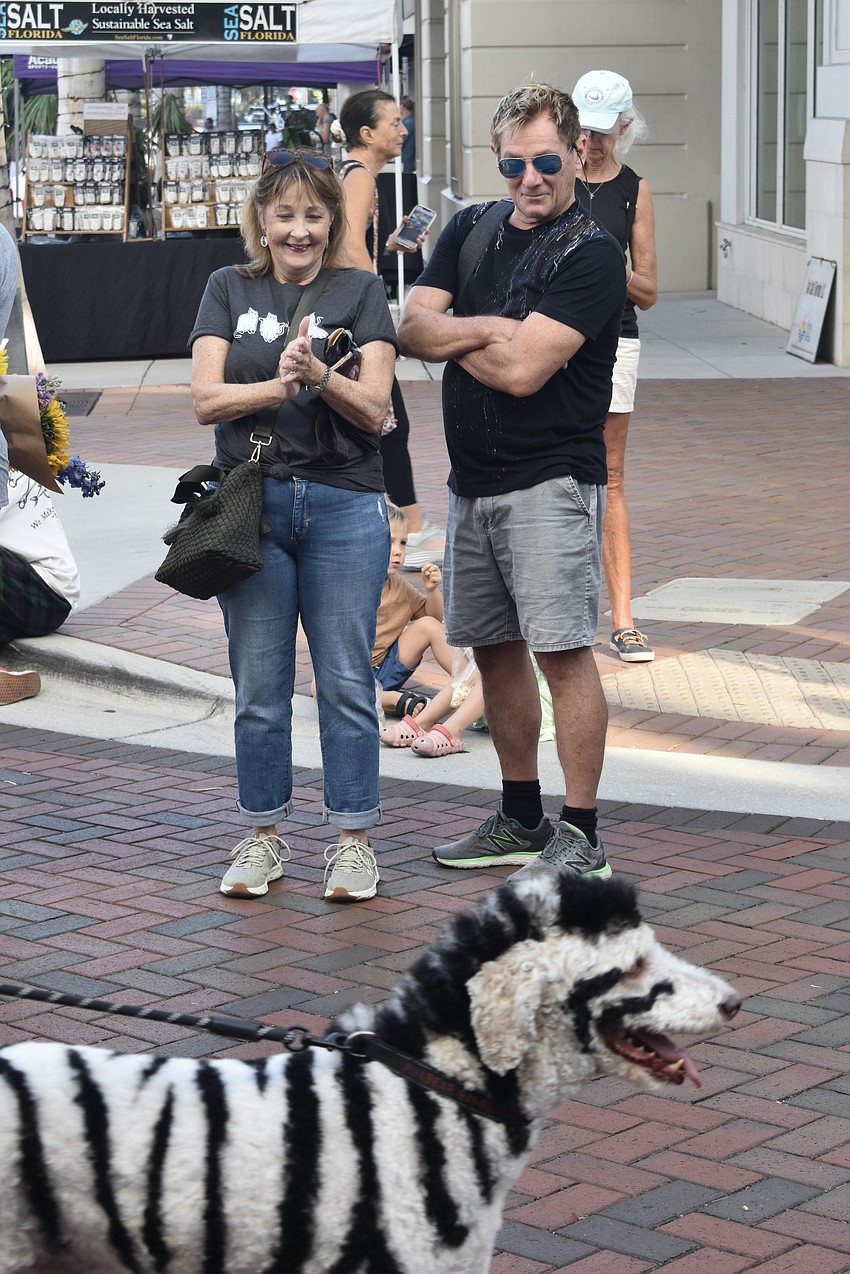 Bystanders Peggy and Mark West watch as the Boff family's dog Bear, in costume as a zebra, parades down the street.