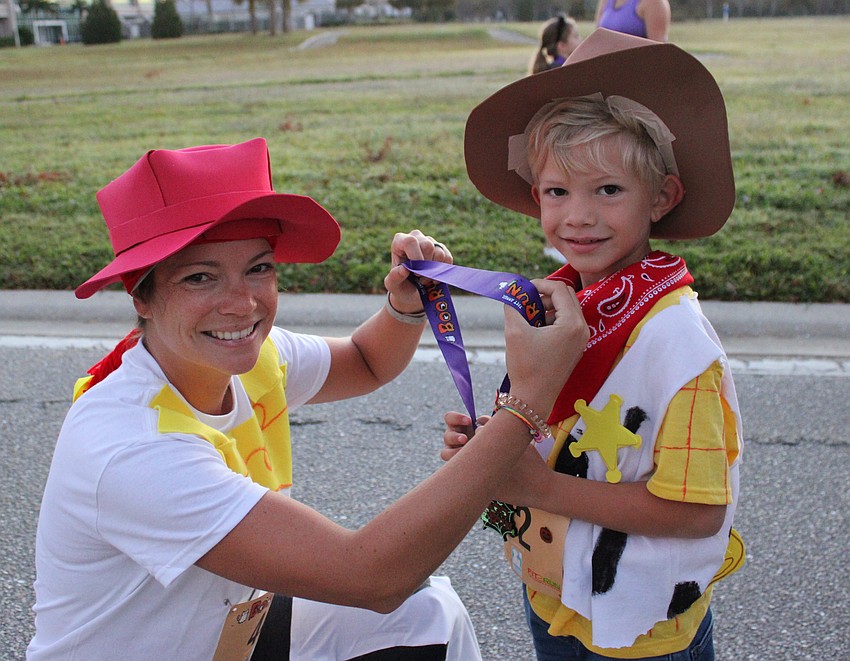 Lakewood Ranch's Ashley Clark of the Lakewood Ranch Running Club, puts a medal on her 5-year-old son Tristan after he competed in the kids run.
