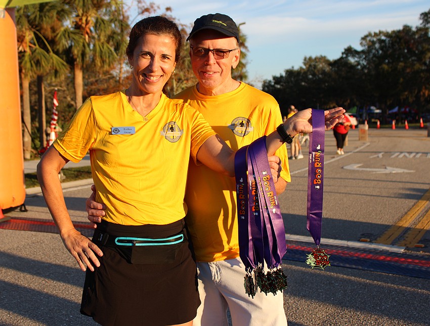 Lakewood Ranch Running Club's Erika Nogueira and Russ Weltzien get ready to hand out runners' medals.