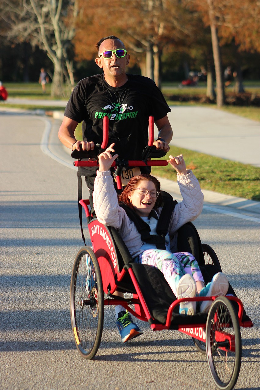 Mallory Schmidt celebrates as Greg Simony pushes her across the finish line in the Boo Run.