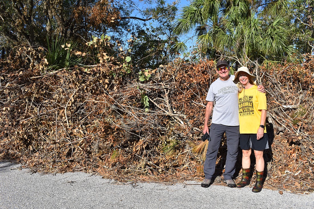 Jim and Susan Eicken stand in front of the giant pile of debris that's mounting in front of their River Club home since Hurricane Milton. They're happy the county will remove it, instead of having to deal with it themselves.