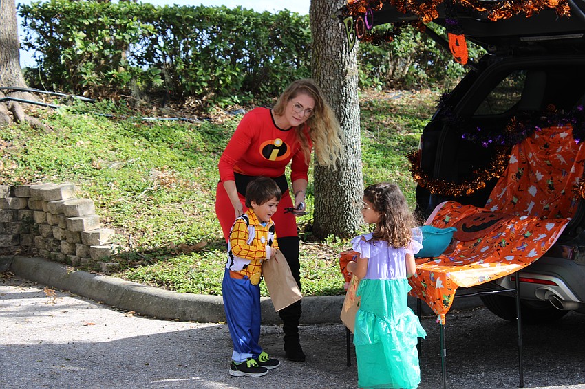 Jessica McCord visits with Kiddie Academy students Emmett Ramirez and Zara Morales during the Halloween parade.