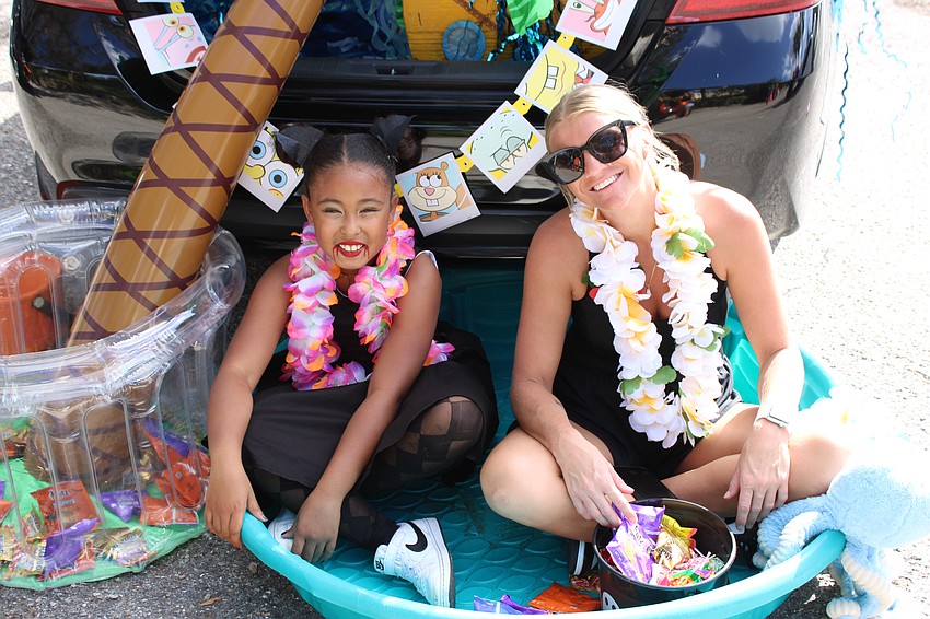 Sophia Marchena, a B.D. Gullett Elementary student, helps Lakewood Ranch's Hailey Hodges hand out candy from a plastic pool during the Kiddie Academy Halloween parade.