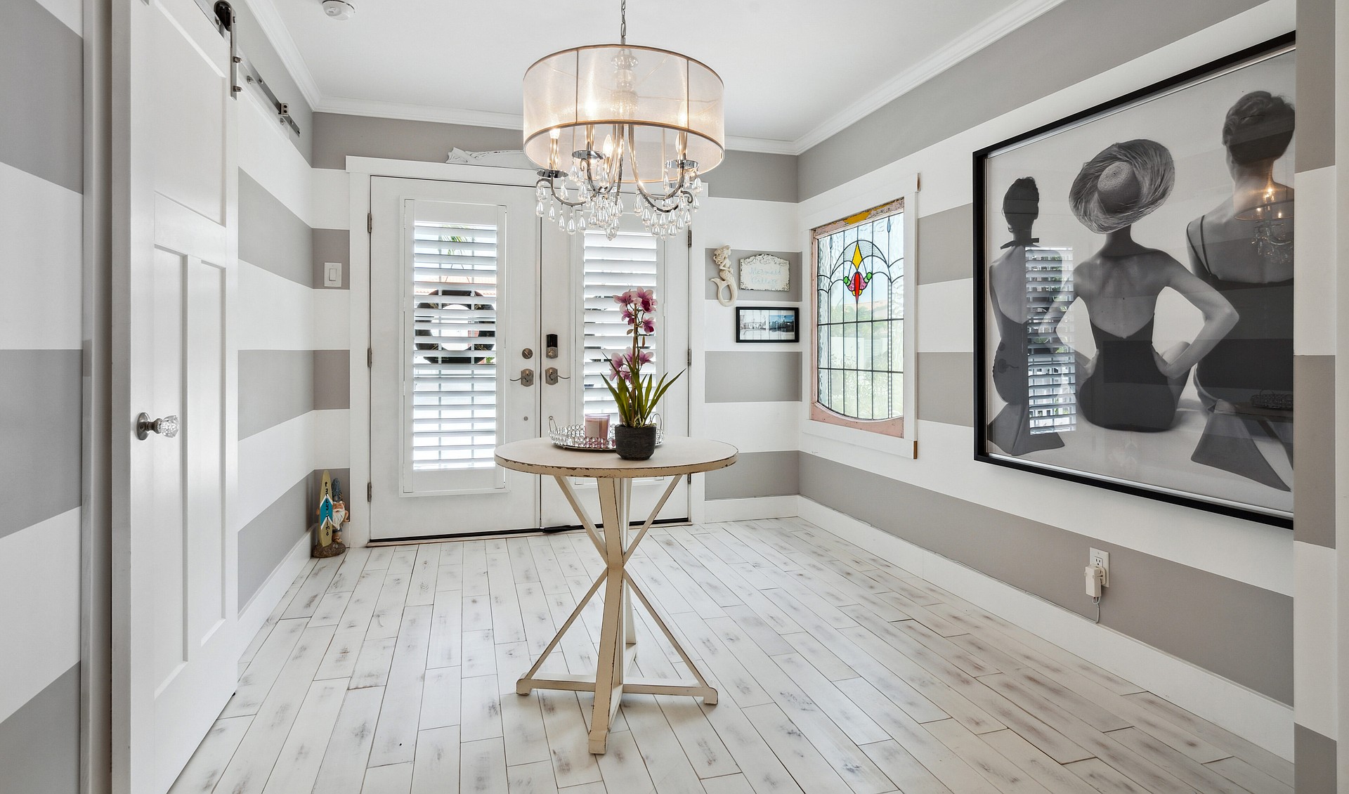 The spacious entrance hallway, adorned in shades of gray and white, features bold graphic art as its centerpiece.