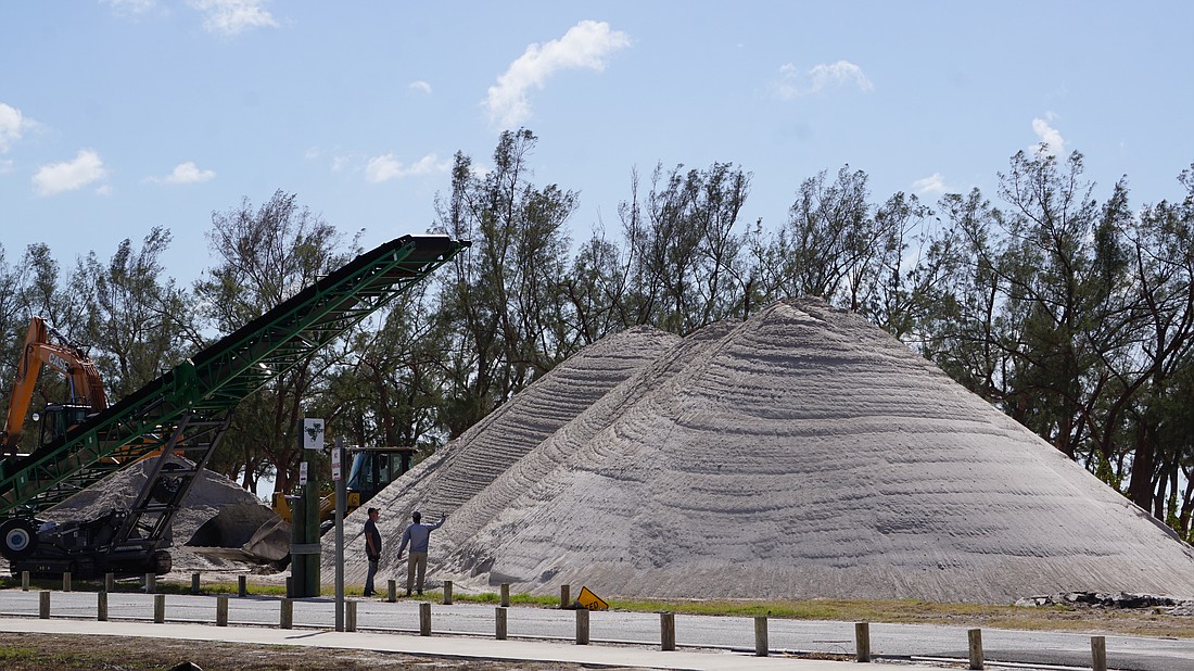 Crews work at the sand pile station at Coquina Beach which sifts sand left behind by Hurricane Helene's surge.