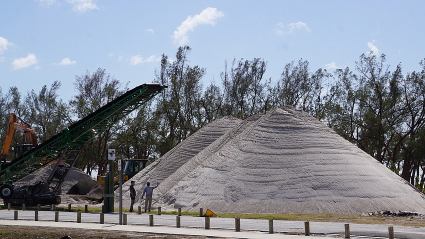 Crews work at the sand pile station at Coquina Beach which sifts sand left behind by Hurricane Helene's surge.