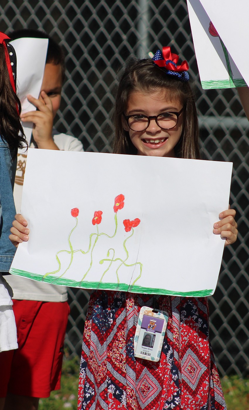 Second grader Teagan Shear shows off the drawing she made for Gilbert McNeal's Veterans Day parade.