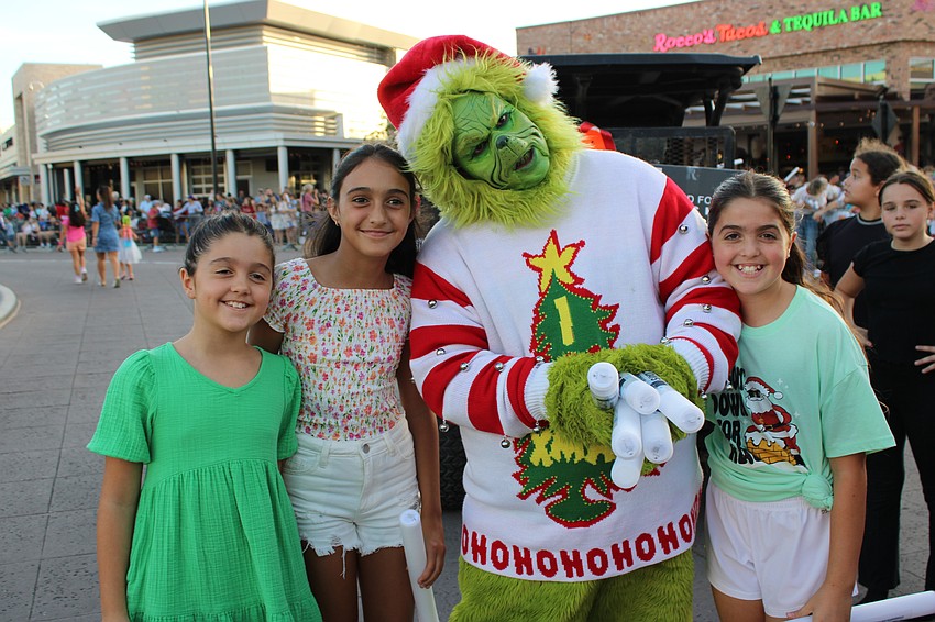 Lakewood Ranch's Alexandra Vassilev, Anastasia Vassilev and Anna Petrovic, try to brighten the Grinch's day at the Santa's Grand Arrival Parade. The Grinch is Kingsley Sim.
