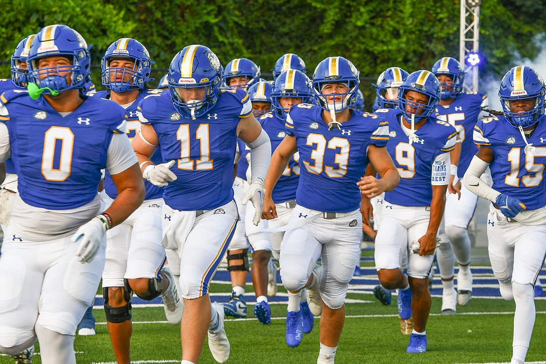 The First Academy football takes the field at Warren Stadium.